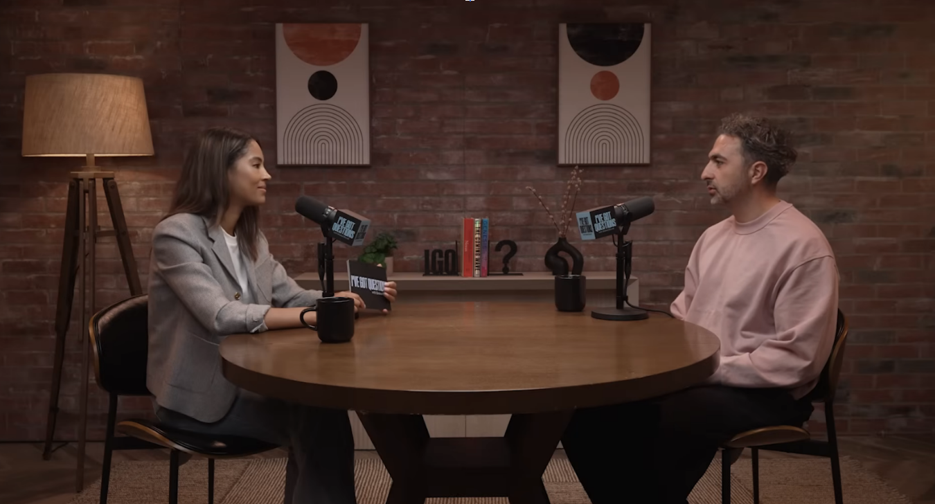 Video Podcast Production at ASL Studios on the living room set. Two people at a table with podcast mics against a brick wall.